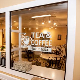 A cozy cafe interior with a sign showing 'Tea & Coffee Served Here.'