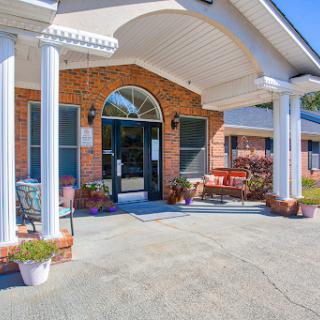An inviting entrance to a beautifully designed home with a spacious porch and decorative plants.