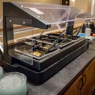 A modern food display setup featuring a variety of meal options under a transparent cover.