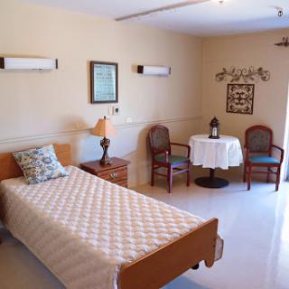 A cozy and well-furnished bedroom with a single bed, a small table, and chairs.