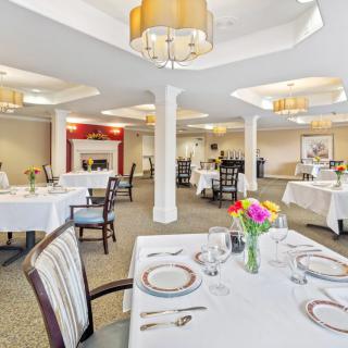 A well-lit dining room with neatly arranged tables and chairs, adorned with flowers and elegant decor.
