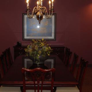 A formal dining room featuring a chandelier, a long dining table with a floral centerpiece, and artwork on the wall.