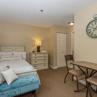 Cozy bedroom with a bed, table and chairs, featuring a decorative wall clock.