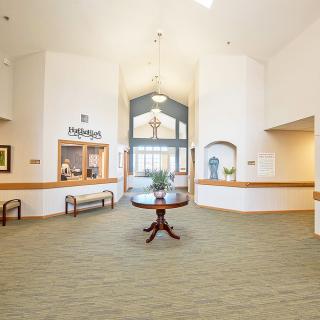 A spacious lobby with a central table and reception desk.