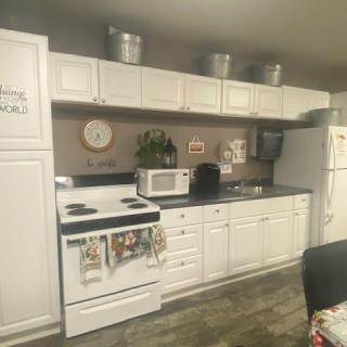 A cozy kitchen with white cabinets and various appliances, including a stove, microwave, and refrigerator.