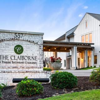 A well-maintained building entrance with a prominent sign and landscaped surroundings.