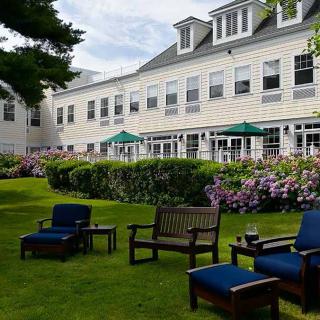 A charming garden area with outdoor seating and a backdrop of a large house.