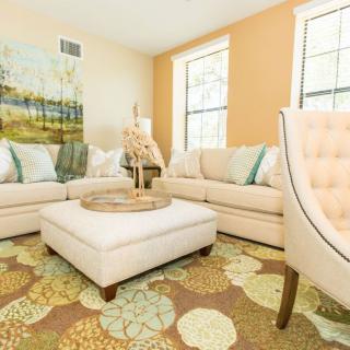 A cozy living room with light-colored furniture and a floral patterned rug.
