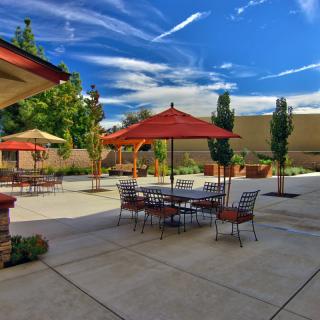 A sunny day on a patio with tables and umbrellas, set against a clear blue sky.