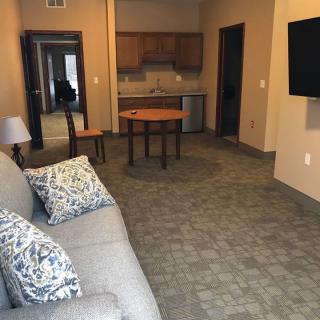 A cozy living room with a sofa, table, chairs, and a TV mounted on the wall.