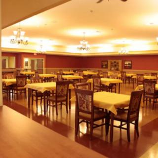 An empty dining area with tables and chairs arranged neatly under warm lighting.