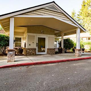The entrance of a suburban building with a covered canopy and landscaped surroundings.