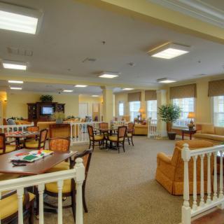A spacious lounge area with tables, chairs, and a television.