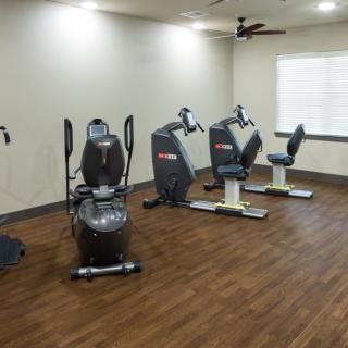 A small indoor gym with exercise machines on a wooden floor.