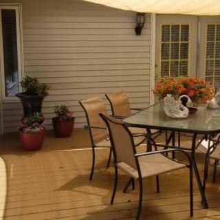 Cozy outdoor patio with a glass table, chairs, and potted plants.