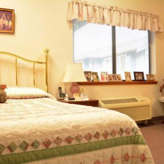 A cozy bedroom with a bed, window, and personal decorations.