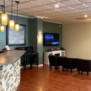 A modern lounge area with a bar counter, pendant lights, and seating facing a television.