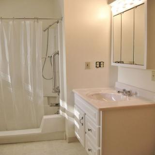 A bright bathroom featuring a sink with a mirror above, and a shower with a curtain.