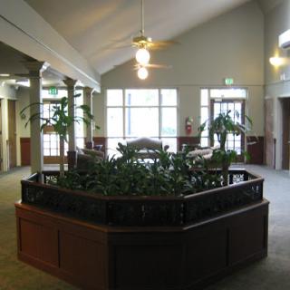 A spacious interior room featuring a central planter with greenery, complemented by wooden accents and ceiling fans.