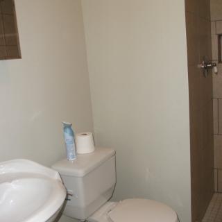 A minimalist bathroom featuring a sink, toilet, and shower.