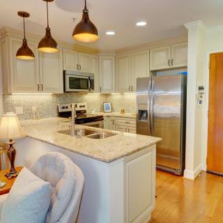 A modern kitchen with a central island, pendant lighting, and stainless steel appliances.