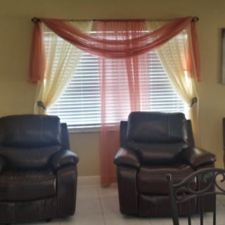 A cozy living room setup featuring two leather chairs and a window with colorful curtains.