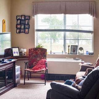 A cozy living room with a large window, comfortable seating, and decorative items.