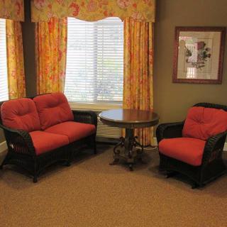 A cozy living room with a sofa, armchair, and a round table by the window.