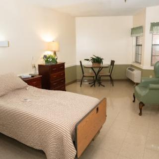 A cozy bedroom featuring a single bed, a small dining table, and simple furnishings.