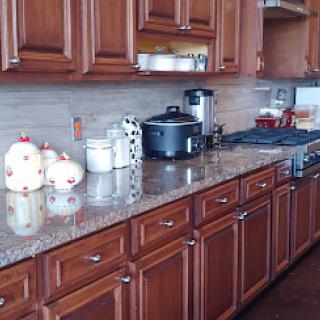 A warm and inviting kitchen with wooden cabinets and a granite countertop, featuring cooking appliances and utensils.