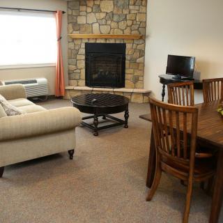 A cozy living room with a stone fireplace, comfortable sofa, and a dining area.