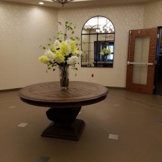 A welcoming lobby with a round wooden table adorned with decorative flowers.