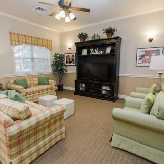 A cozy living room with patterned sofas, armchairs, and a large entertainment center.