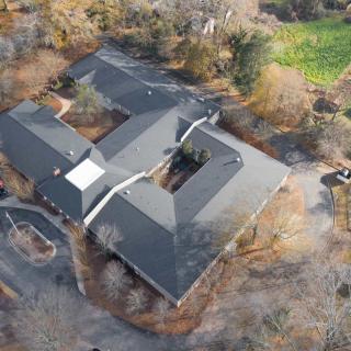 Aerial view of a large building surrounded by trees and natural landscape.