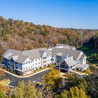 Aerial view of a large building surrounded by autumn trees and a parking lot.
