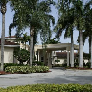 A scenic view of a building entrance with palm trees and well-maintained landscaping.
