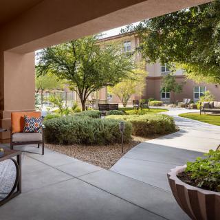 A peaceful outdoor patio with seating, surrounded by lush greenery and a well-maintained garden.
