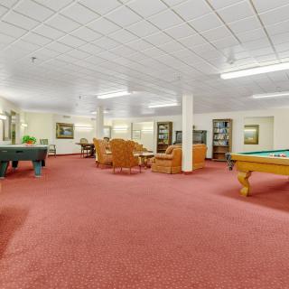 A spacious recreation room featuring pool tables and comfortable seating areas.