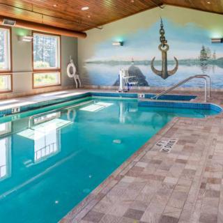 An indoor swimming pool with a nautical-themed mural on the wall and windows allowing natural light in.
