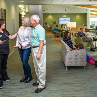 A healthcare staff member engages with elderly patients in a welcoming waiting area.