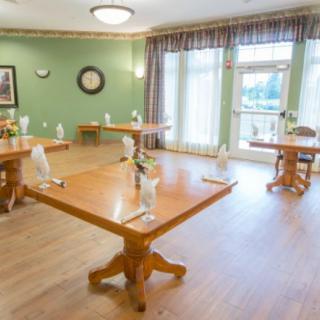 A neatly arranged dining area with wooden tables and chairs in a warmly lit room.