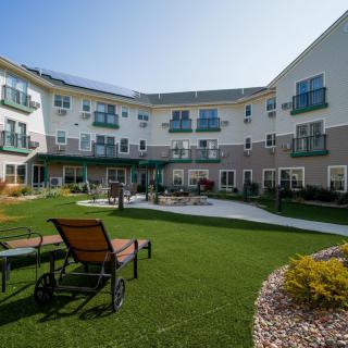 A courtyard with loungers on the lawn surrounded by a multi-story building under a clear sky.