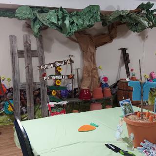 A vibrant garden-themed decoration setup with a large tree and colorful flowers, perfect for a party or craft event.