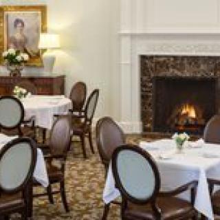 A formal dining room featuring elegantly set tables and a warm fireplace.