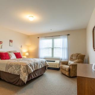 A cozy bedroom interior with a comfortable bed and an armchair next to the window.