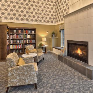 A cozy reading nook featuring a fireplace, comfortable seating, and a well-stocked bookshelf.