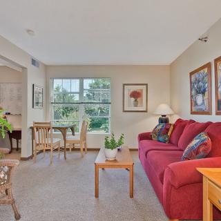 A cozy living room with a red couch, coffee table, and adjacent dining area.
