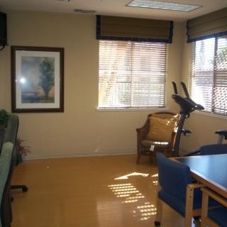 A small office space with exercise equipment and natural light coming through the windows.