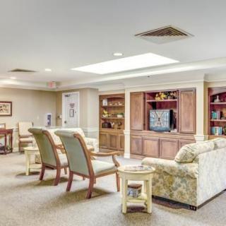 A cozy and well-furnished living room with sofas, chairs, a television, and built-in shelves.