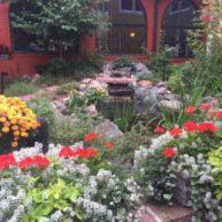 A beautifully landscaped garden with vibrant flowers and a central water feature.
